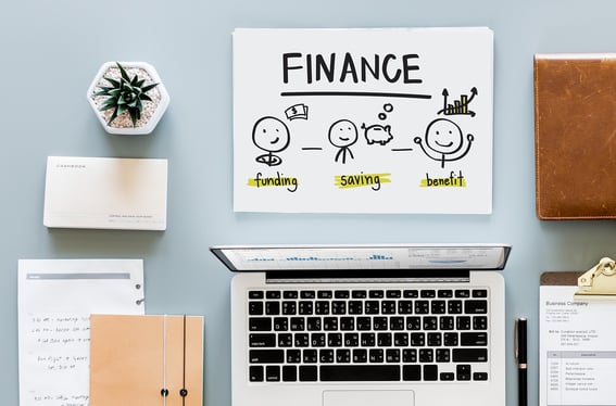 an orderly set of tools for GAAP accounting, including a laptop, notebooks, pen, ledger, and desk plant